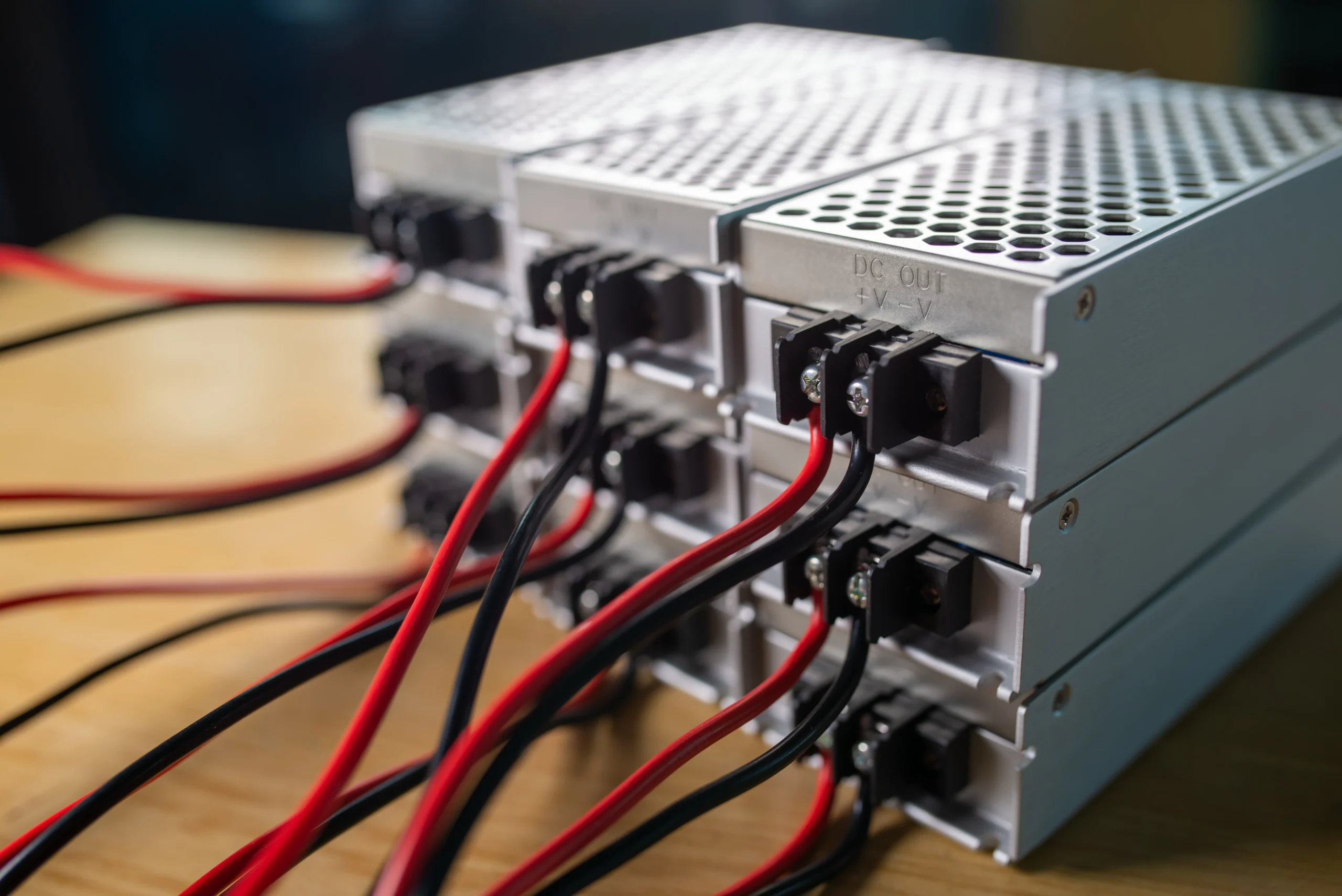 Close-up view of LED power supply units with red and black wires connected, showcasing a professional power setup.